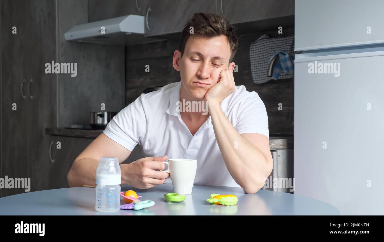 Der verschnaufte Vater nippt und trinkt eine Tasse Kaffee in der Küche Stockfoto