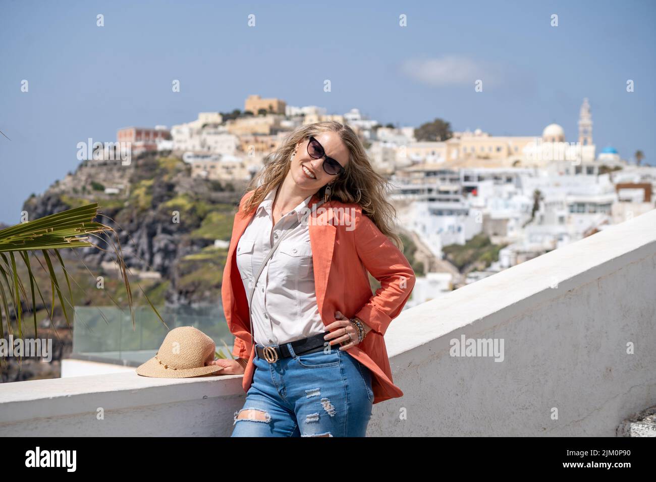 Eine flache Aufnahme einer schönen kaukasischen Frau in stilvoller Kleidung vor dem Hintergrund der einzigartigen Architektur von Santorini, Griechenland Stockfoto