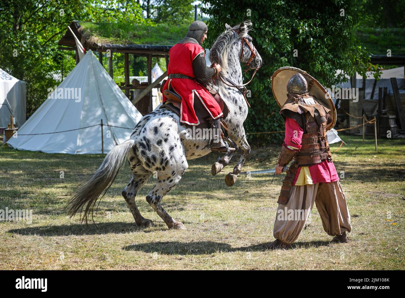 Ratzeburg, 31. Juli 2022: Ritter auf einem aufsteigenden Pferd und ein Krieger mit Schild zu Fuß, der eine Kampfdemonstration bei einem mittelalterlichen Fest zeigt Stockfoto