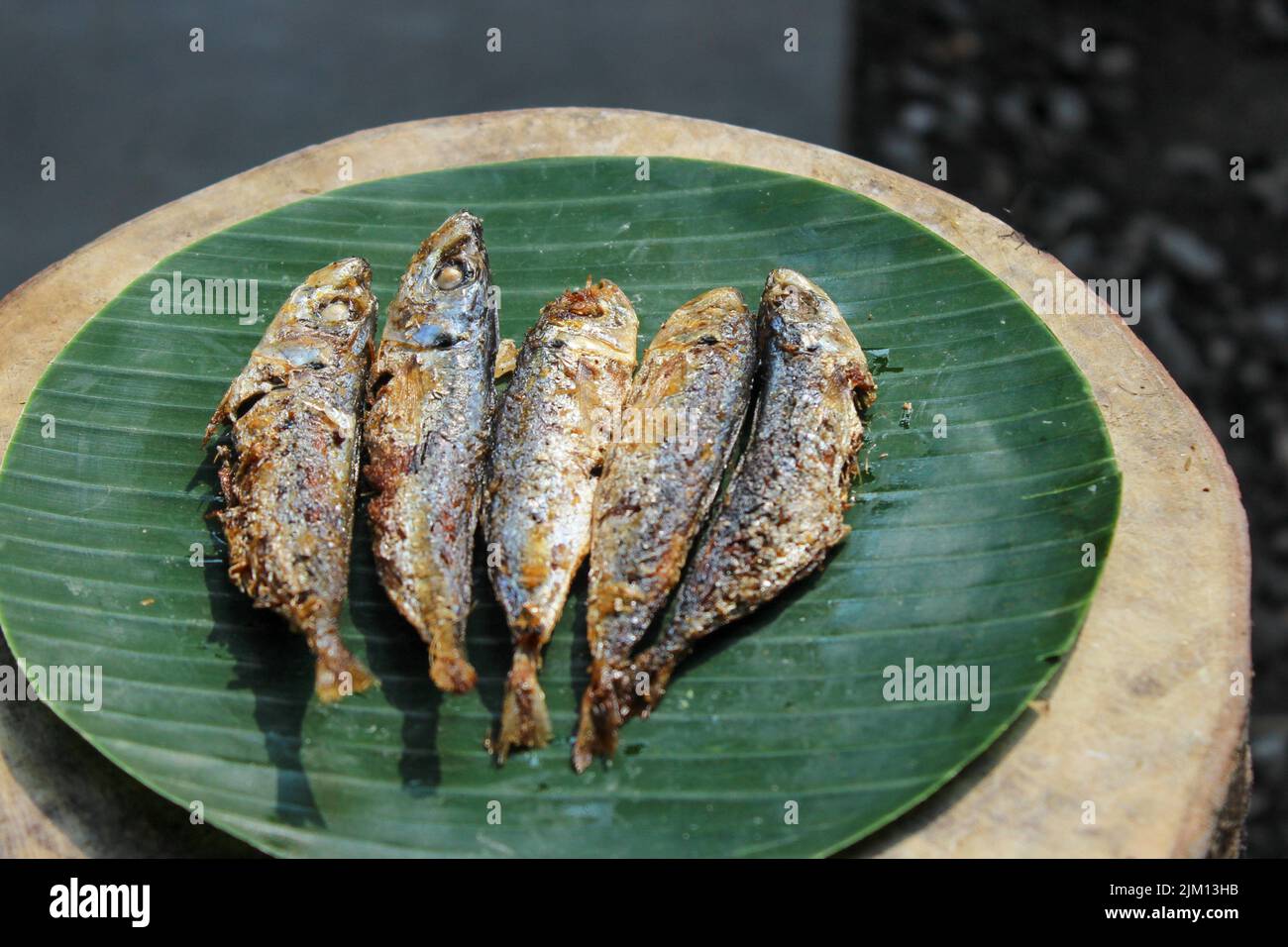 indonesische authentische Lebensmittel gebratener gesalzener Fisch oder ikan asin gereh auf Holzoberfläche mit Bananenblatt. Stockfoto