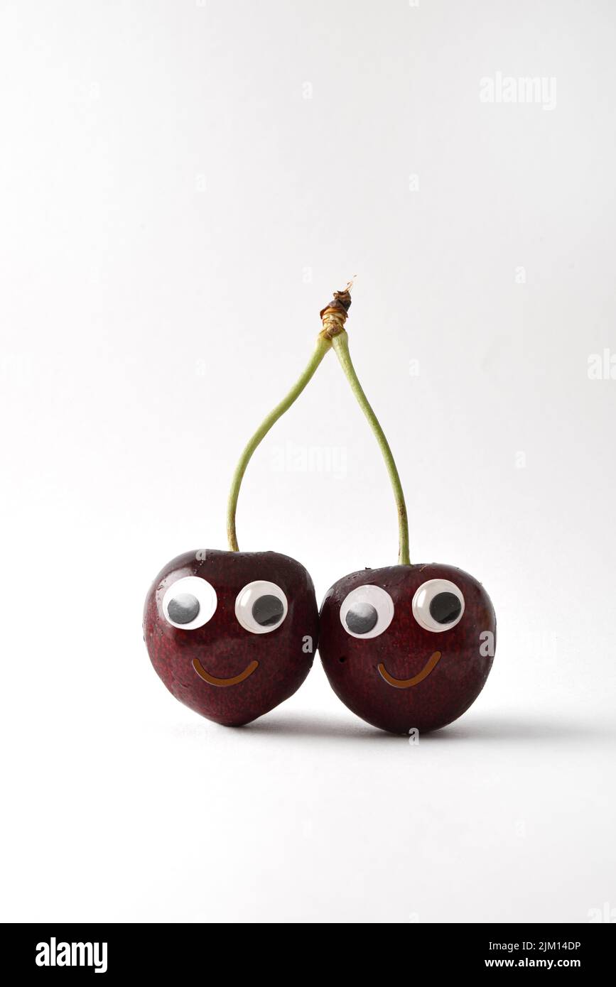 Gesunde frische Kirschen mit Gesicht auf weißem, isoliertem Hintergrund. Obst und Gemüse Kind gesunde Ernährung Konzept Stockfoto