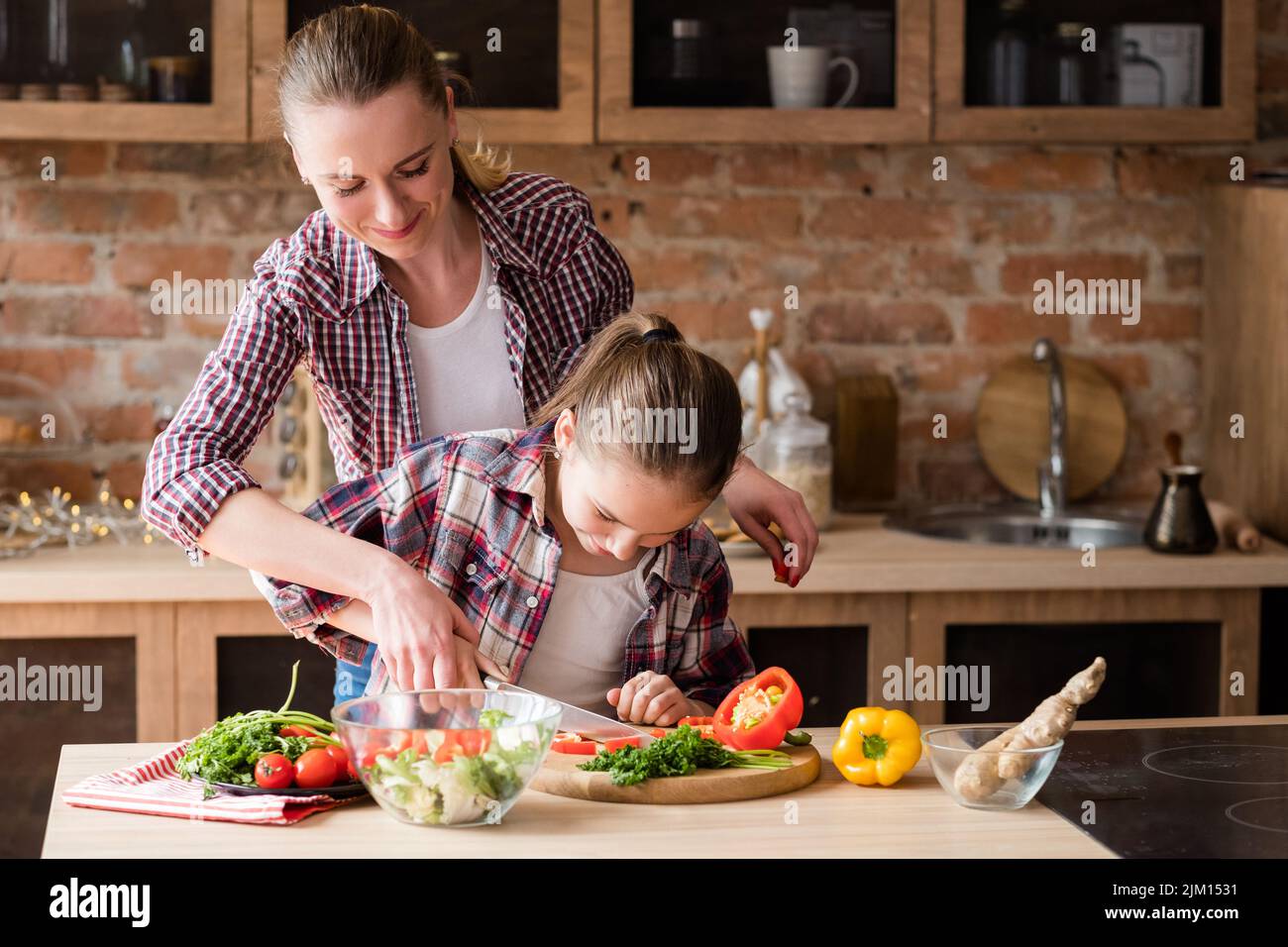 Familie Kochen Mutter lehren Tochter geschnitten Gemüse Stockfoto