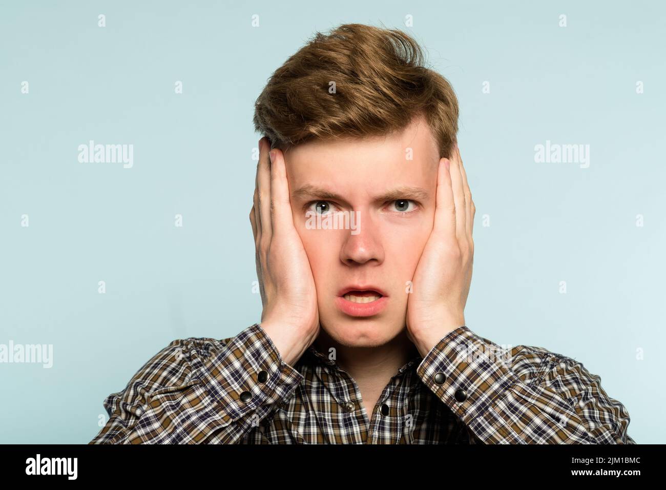 Schockiert verwundert verwirrt Mann hält Kopf Hände Stockfoto