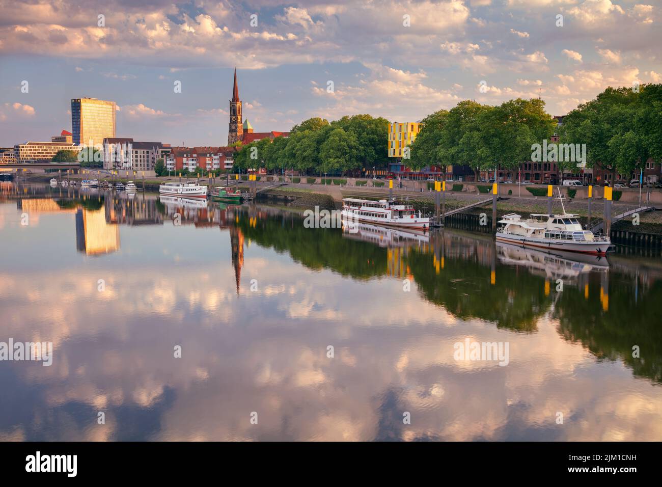 Bremen, Deutschland. Stadtbild des Bremer Flussufers mit Spiegelung der Stephani-Kirche in der Weser bei Sommersonnenaufgang. Stockfoto