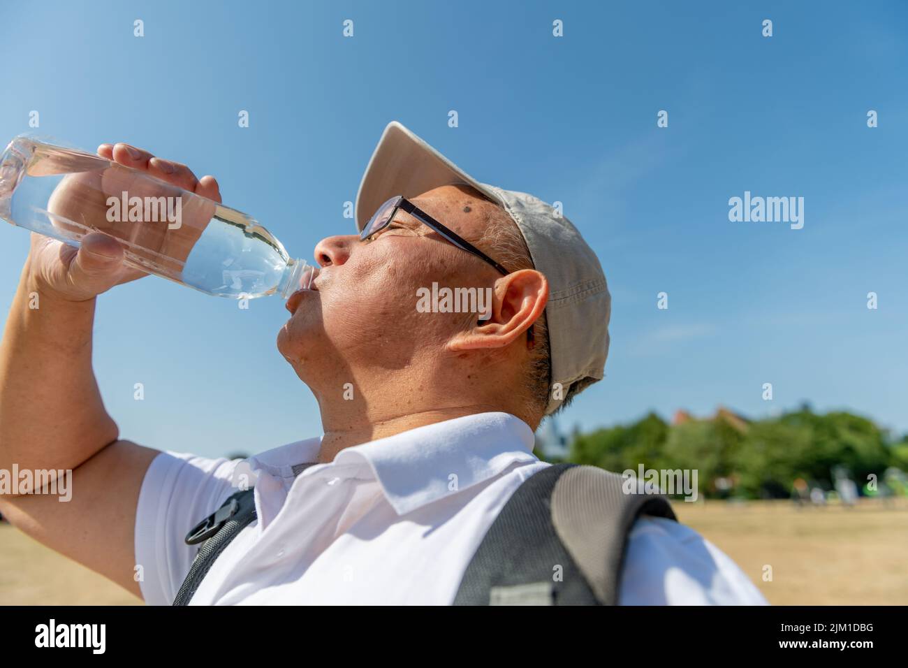 Ein älterer Mann trinkt viel Wasser an einem rekordverdächtigen heißen Sommertag, um Austrocknung unterwegs zu vermeiden. Stockfoto