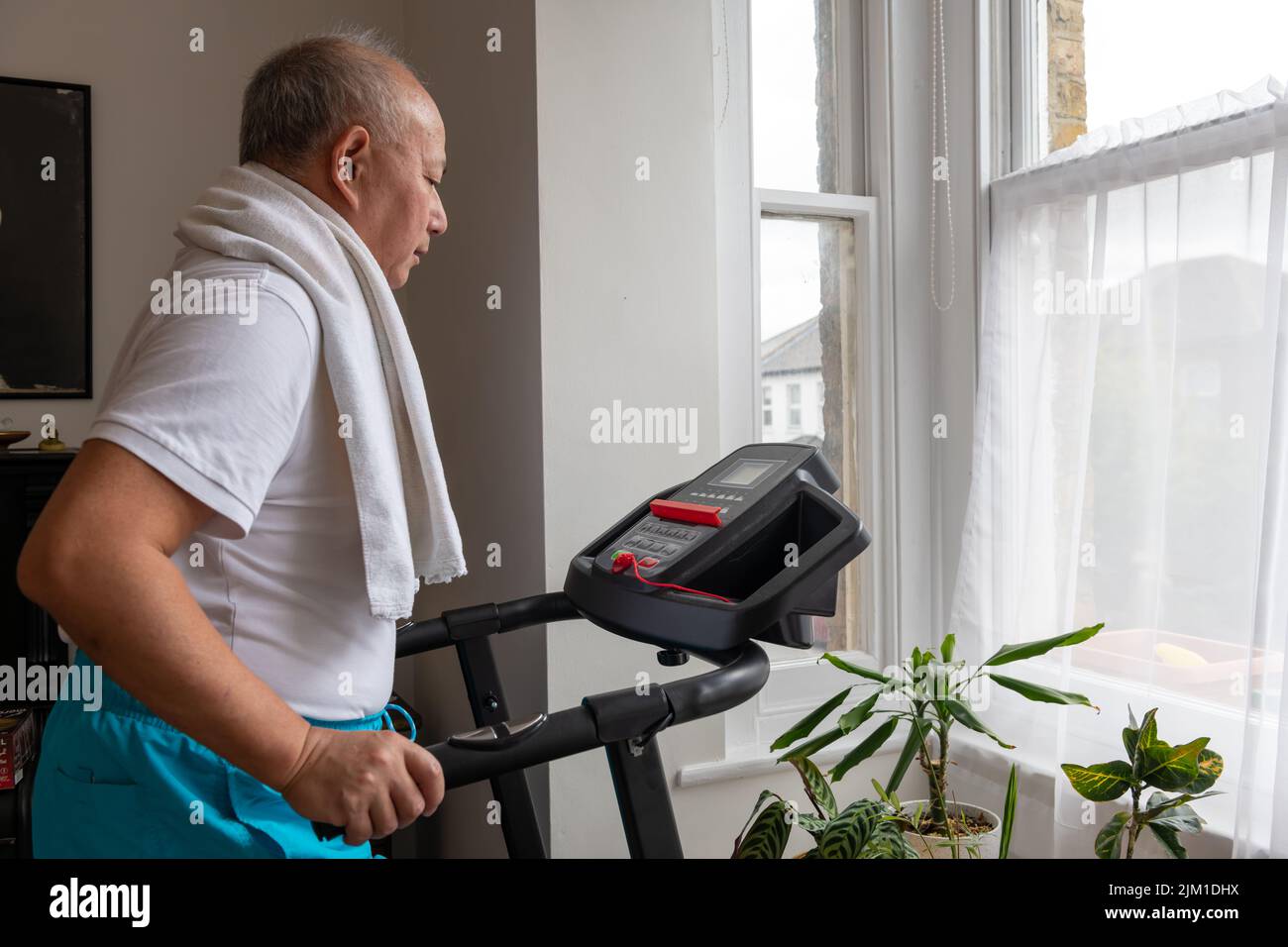 Ein älterer Mann, der zu Hause auf dem Laufband fit bleiben möchte. Stockfoto