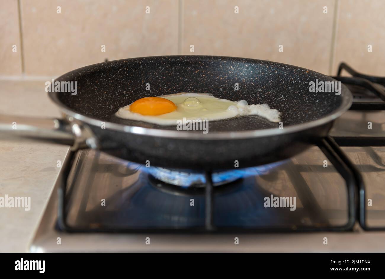 Eine Bratpfanne auf einem Herd, der Gas verbrennt. Konzept der steigenden Energieverbrauchskosten. Energiekrise. Stockfoto