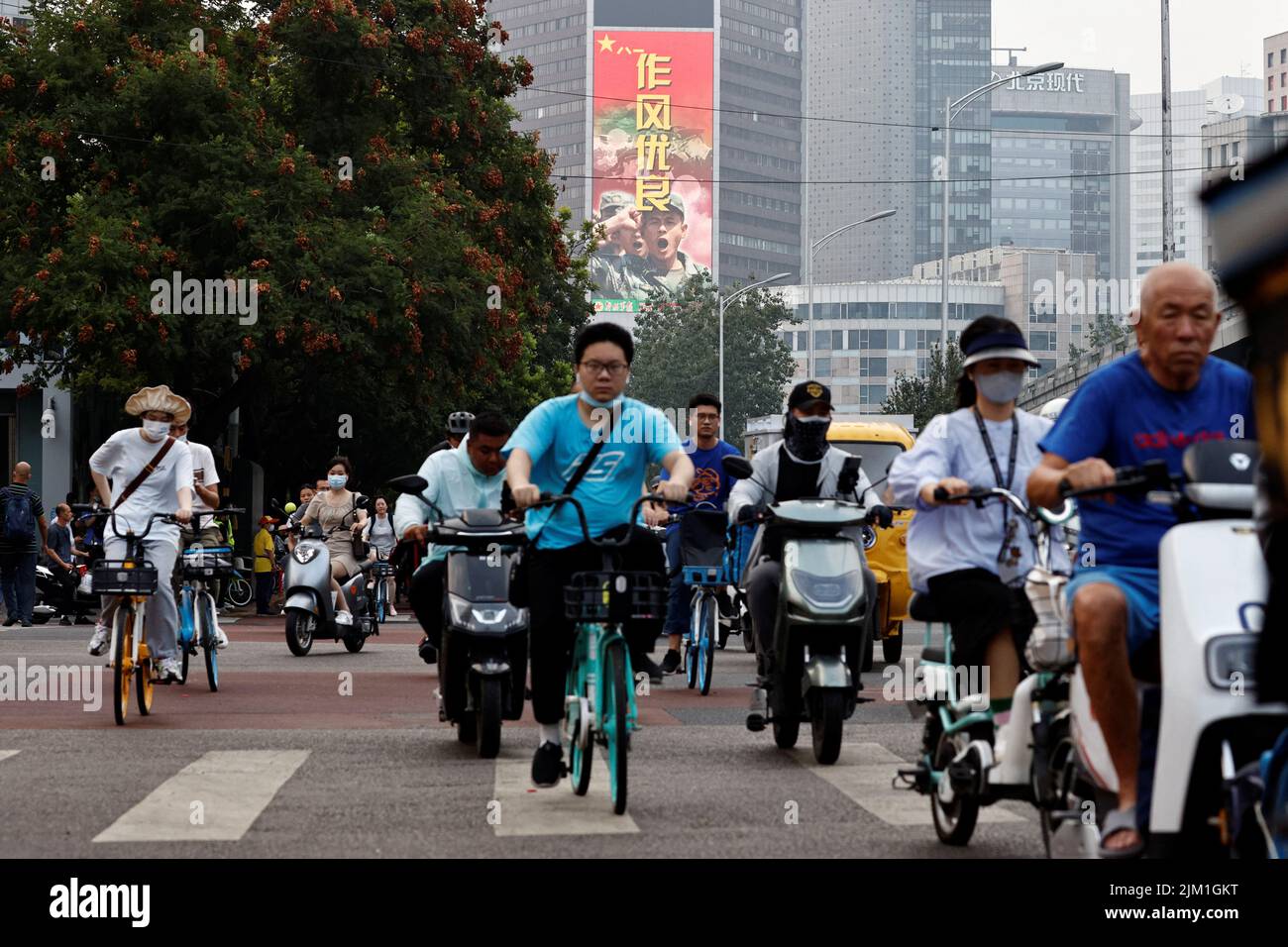 Menschen fahren Fahrzeuge in der Nähe eines Bildschirms, auf dem ein Bild der chinesischen Volksbefreiungsarmee (PLA) in Peking, China, am 4. August 2022 angezeigt wird. REUTERS/Thomas Peter Stockfoto