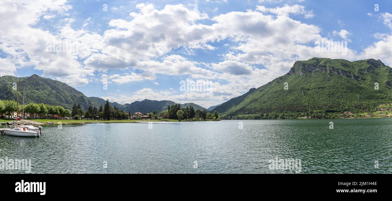 Panoramablick auf die bewaldeten Alpen und den höchsten lombardischen Idrosee (Lago d'Idro), mehrere Boote auf dem Pier in der Nähe des Ufers. Brescia, Lombardei, Italien Stockfoto