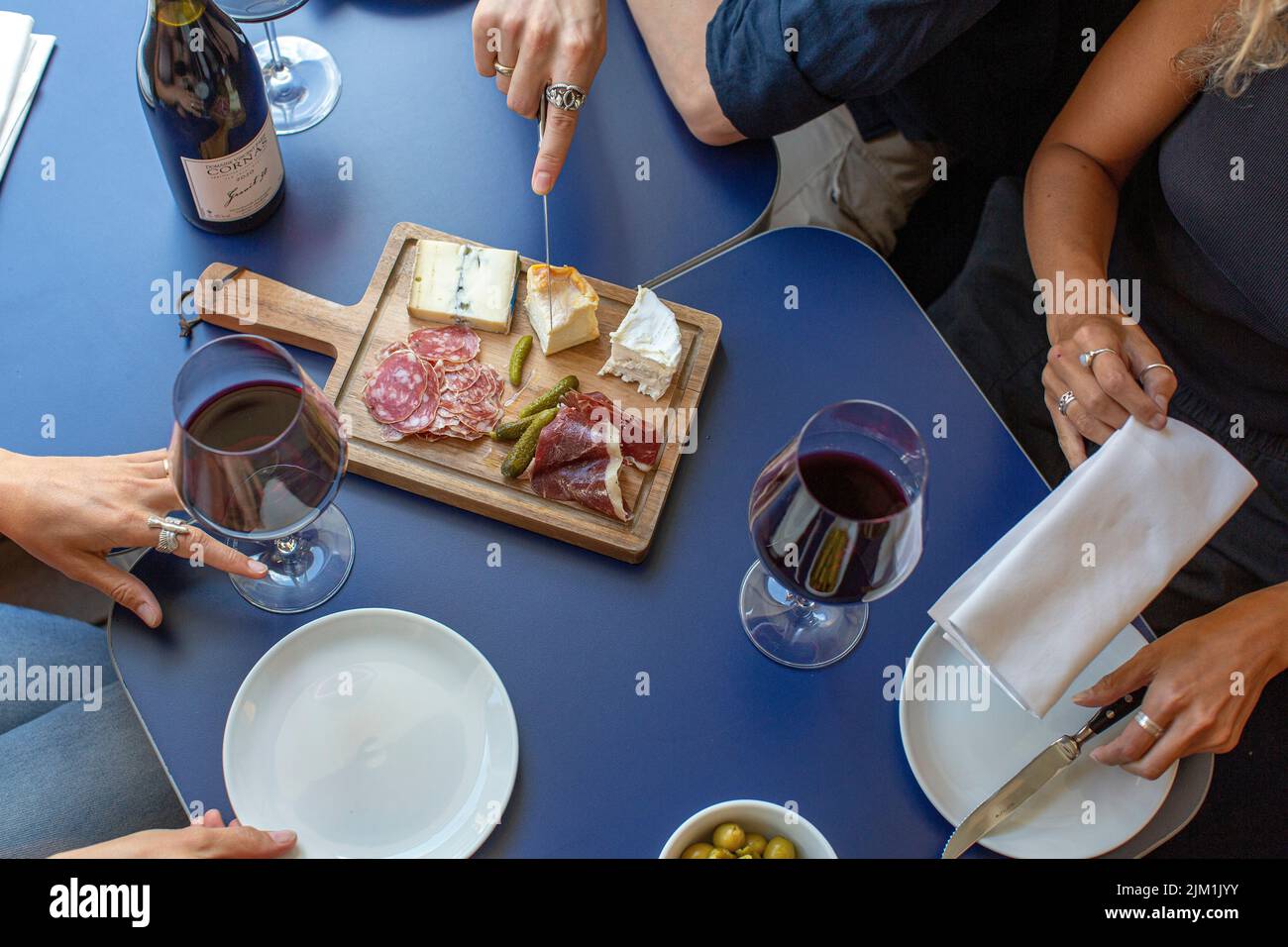 Rotwein, Wurstwaren und Käseplatte, Rotwein, Snacks und Menschenhände Stockfoto