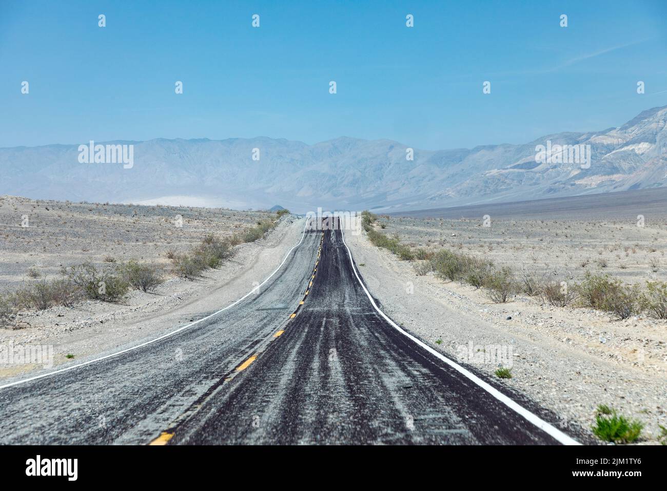 Leere gerade Straße durch das Death Valley mit gelbem Median, USA Stockfoto
