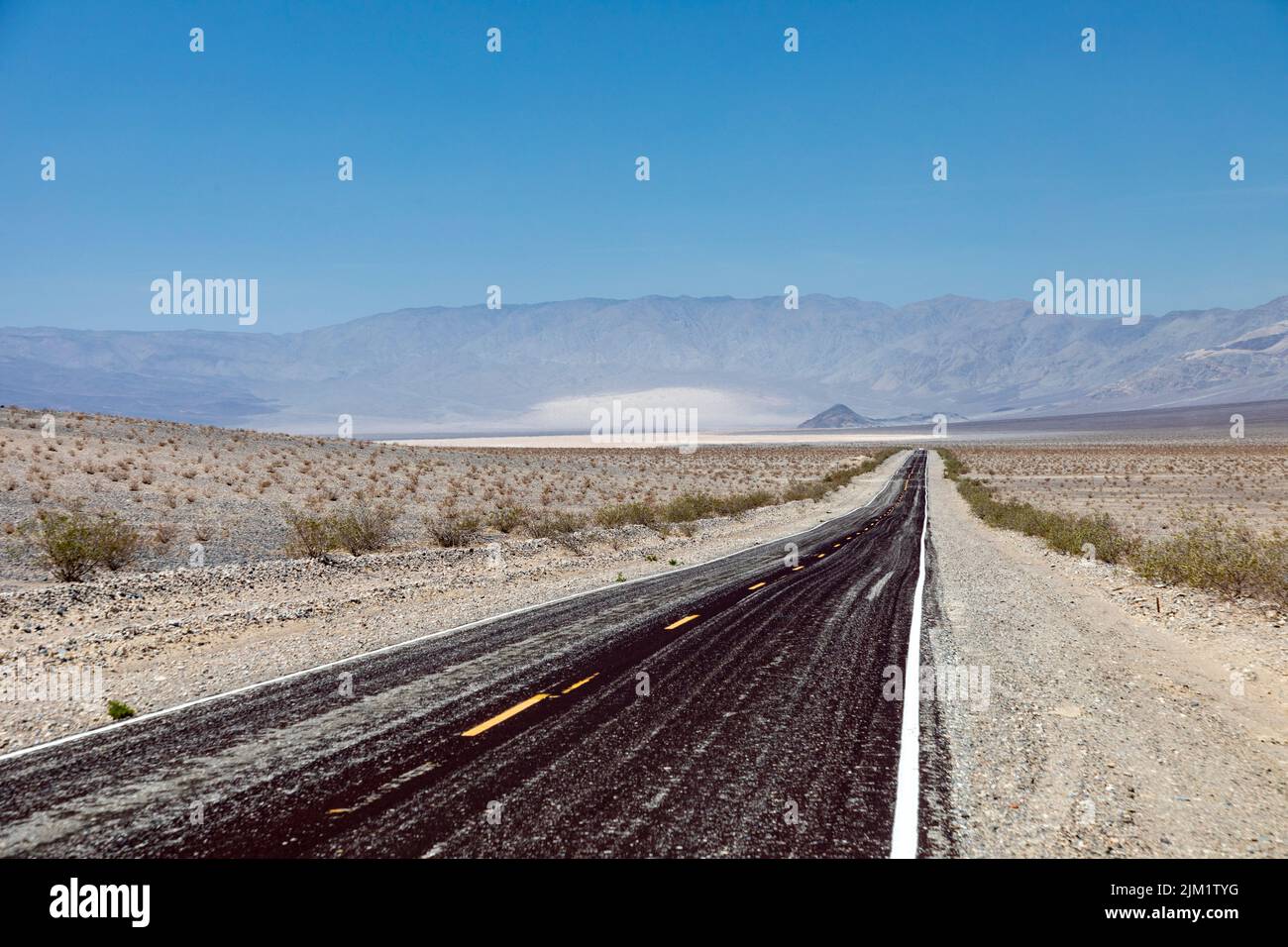 Leere gerade Straße durch das Death Valley mit gelbem Median, USA Stockfoto