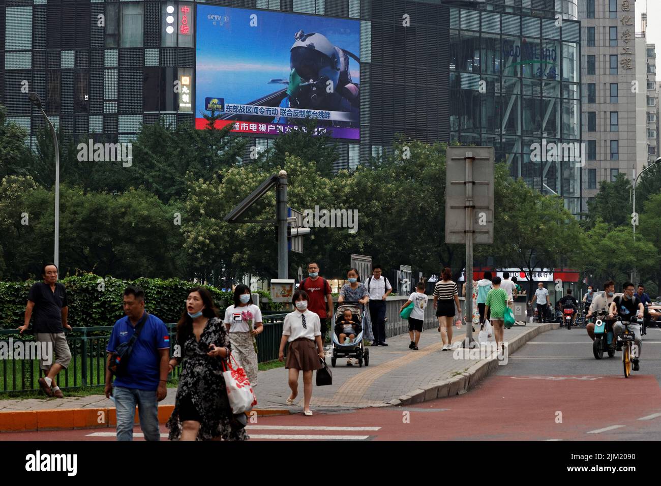 Fußgänger gehen an einem riesigen Bildschirm vorbei, der Nachrichtenberichte über die militärischen Übungen der chinesischen Volksbefreiungsarmee (PLA) in Peking, China, in Taiwan, am 4. August 2022, sendet. REUTERS/Thomas Peter Stockfoto