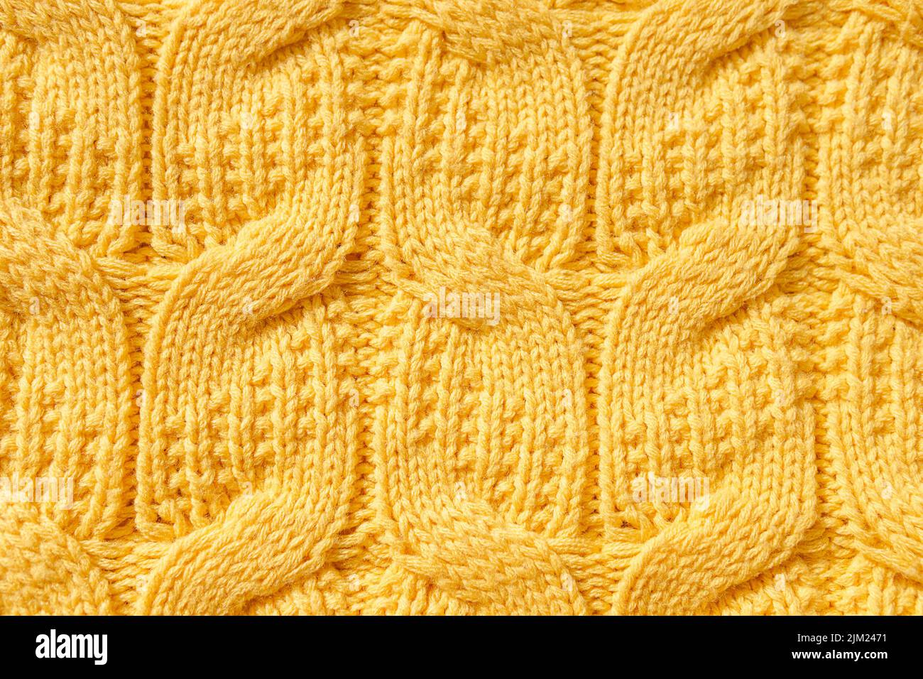 Die Textur eines warmen Strickpullovers. Der perfekte Hintergrund ist gelb. Nahaufnahme Stockfoto