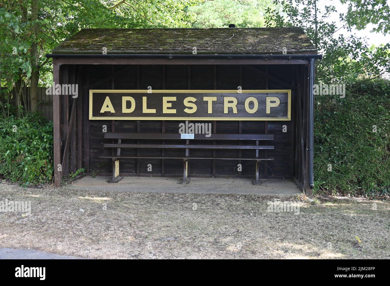 Bahnhofsbank und Schild des alten Bahnhofs im Dorf Adlestrop in Gloucestershire in der Nähe von Stow on the Wold. Jetzt als Busunterstand genutzt Stockfoto