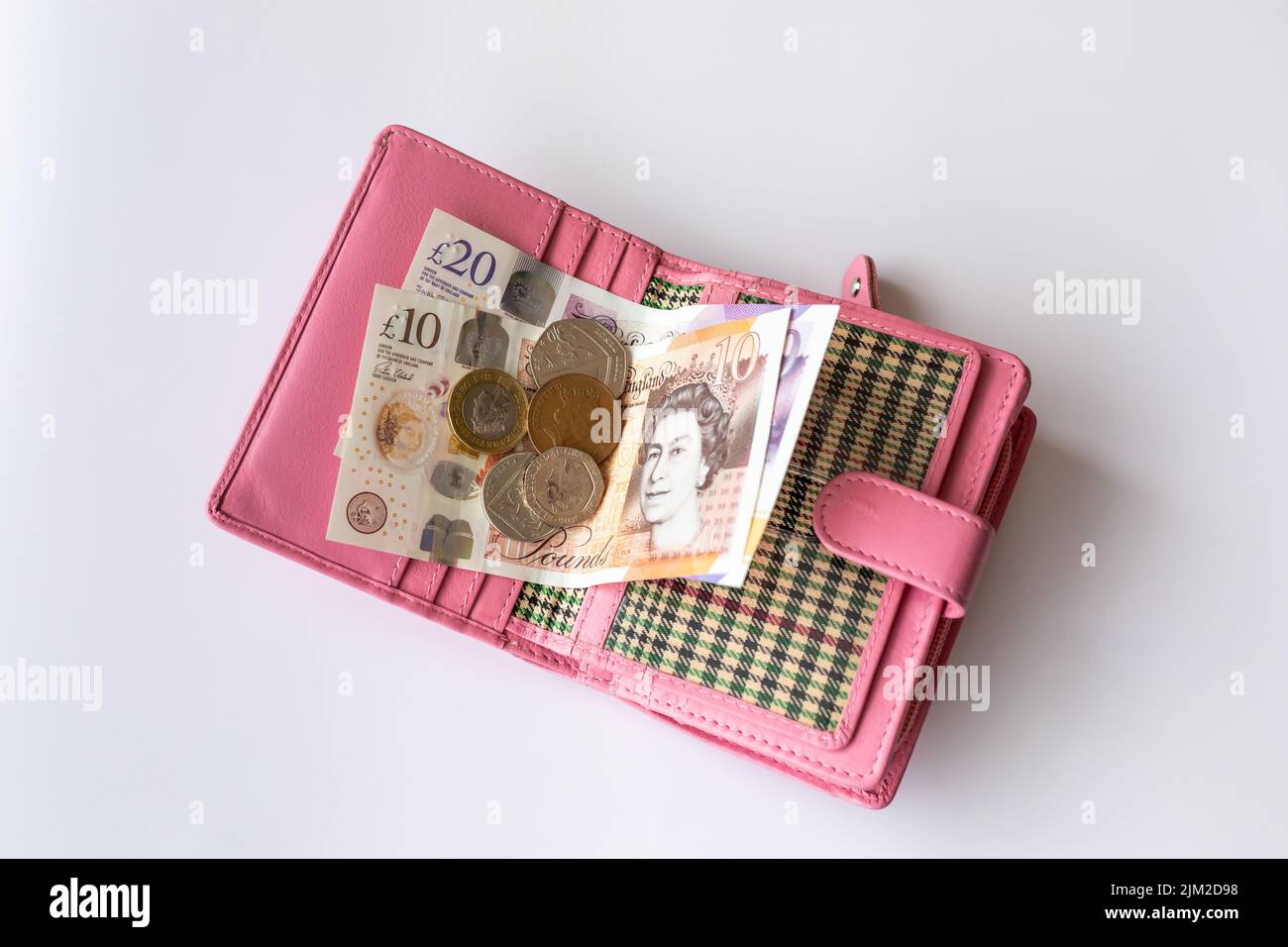 Rosa Geldbörse mit englischen Banknoten und Münzen aus der Nähe. Stockfoto