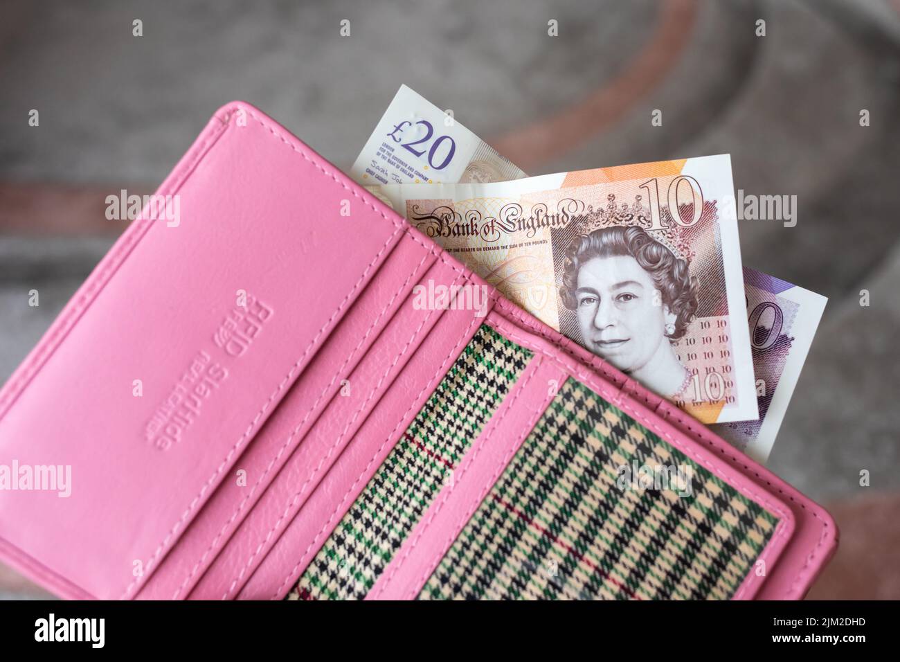 Rosa Geldbörse mit englischen Banknoten aus der Nähe. Stockfoto