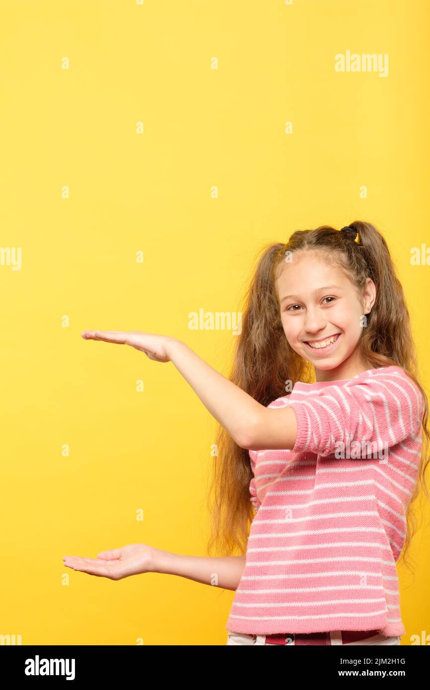 Lächelndes Mädchen hält große virtuelle Objekt leere Hand Stockfoto