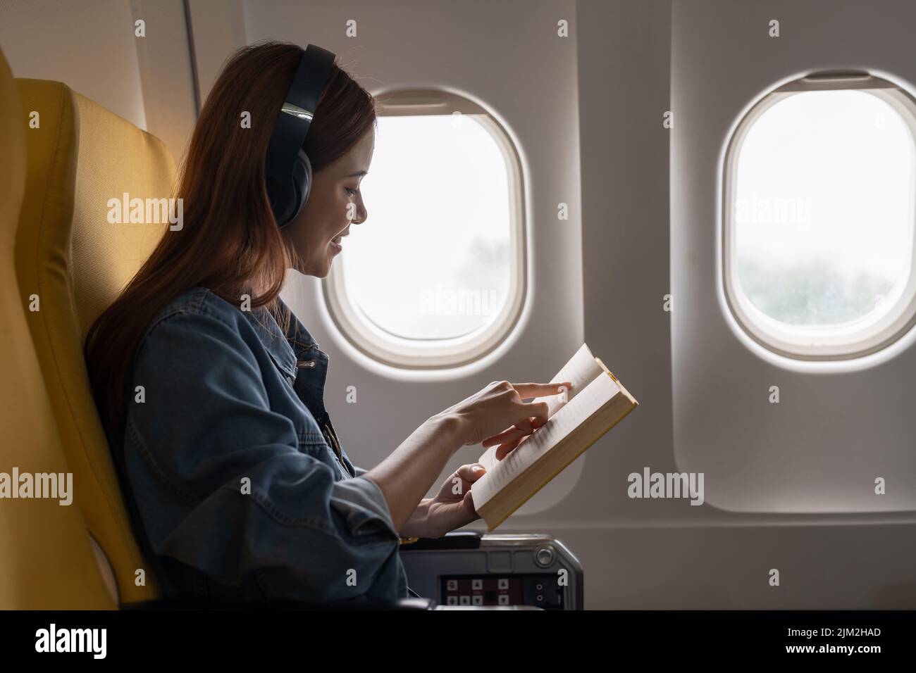 Schöne asiatische Reise Frau liest ein Buch im Flugzeug Stockfoto