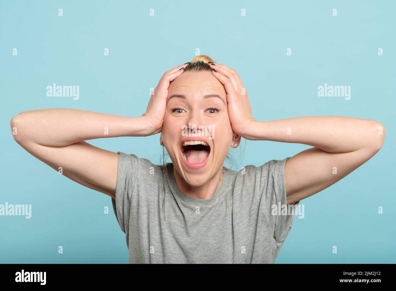 Aufgeregte enthusiastische Frau schreit, halte die Kopfhände Stockfoto