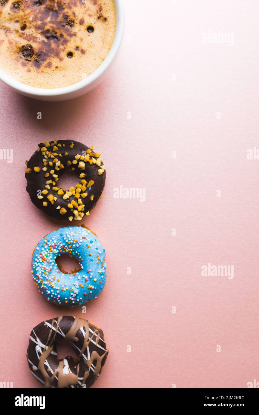 Overhead-Ansicht von frischem Schokoladengetränk in Tasse von Donuts und Kopierraum vor farbigem Hintergrund Stockfoto
