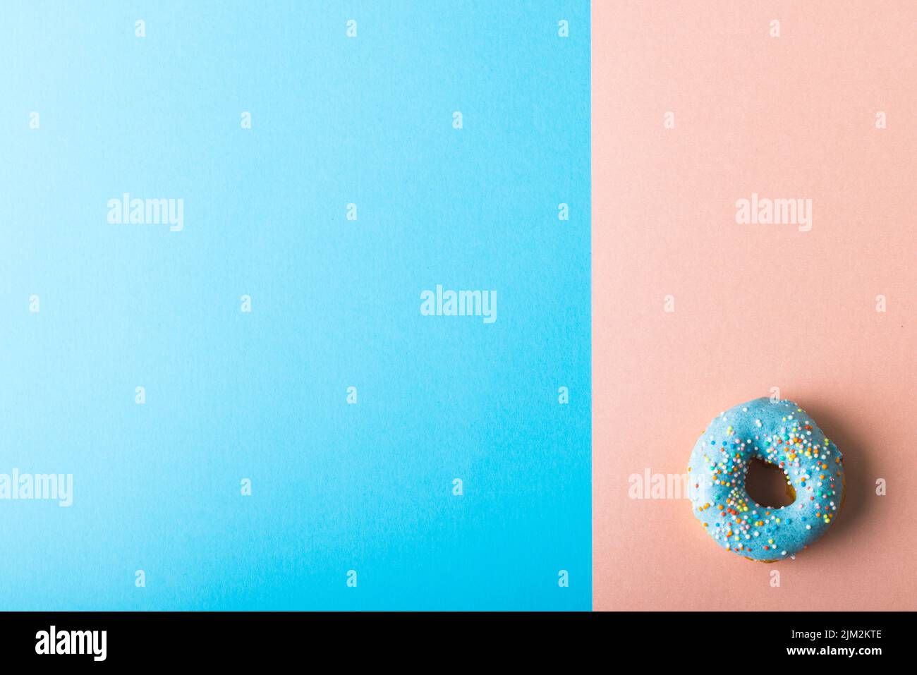 Direkt über der Ansicht des frischen blauen Donuts mit Sprinklern durch einen Kopierraum auf zweifarbigem Hintergrund Stockfoto