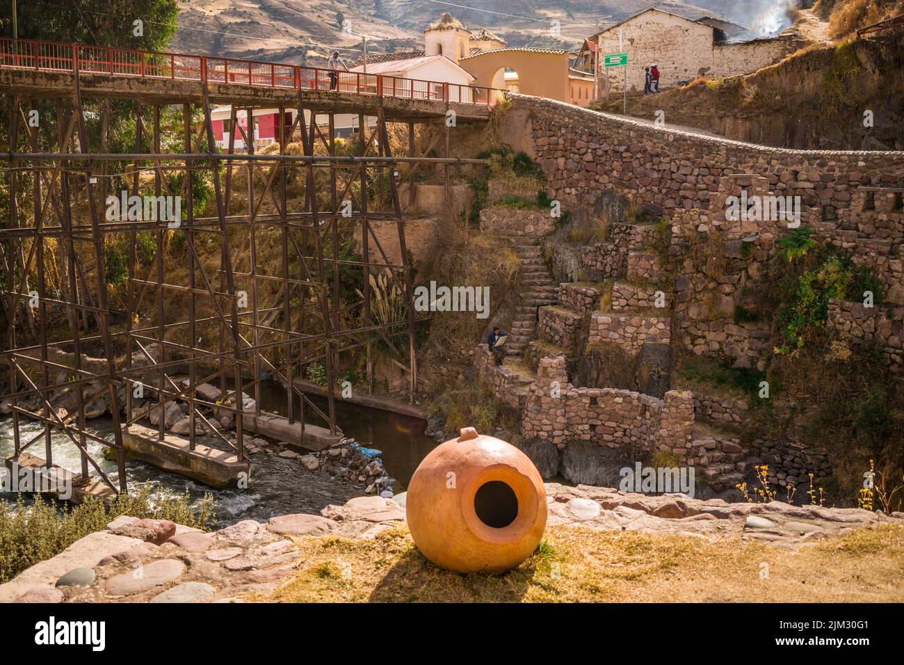 Tontopf mit Fluss in der Nähe von Steinbau und Metallbrücke in checacupe, cusco, peru Stockfoto