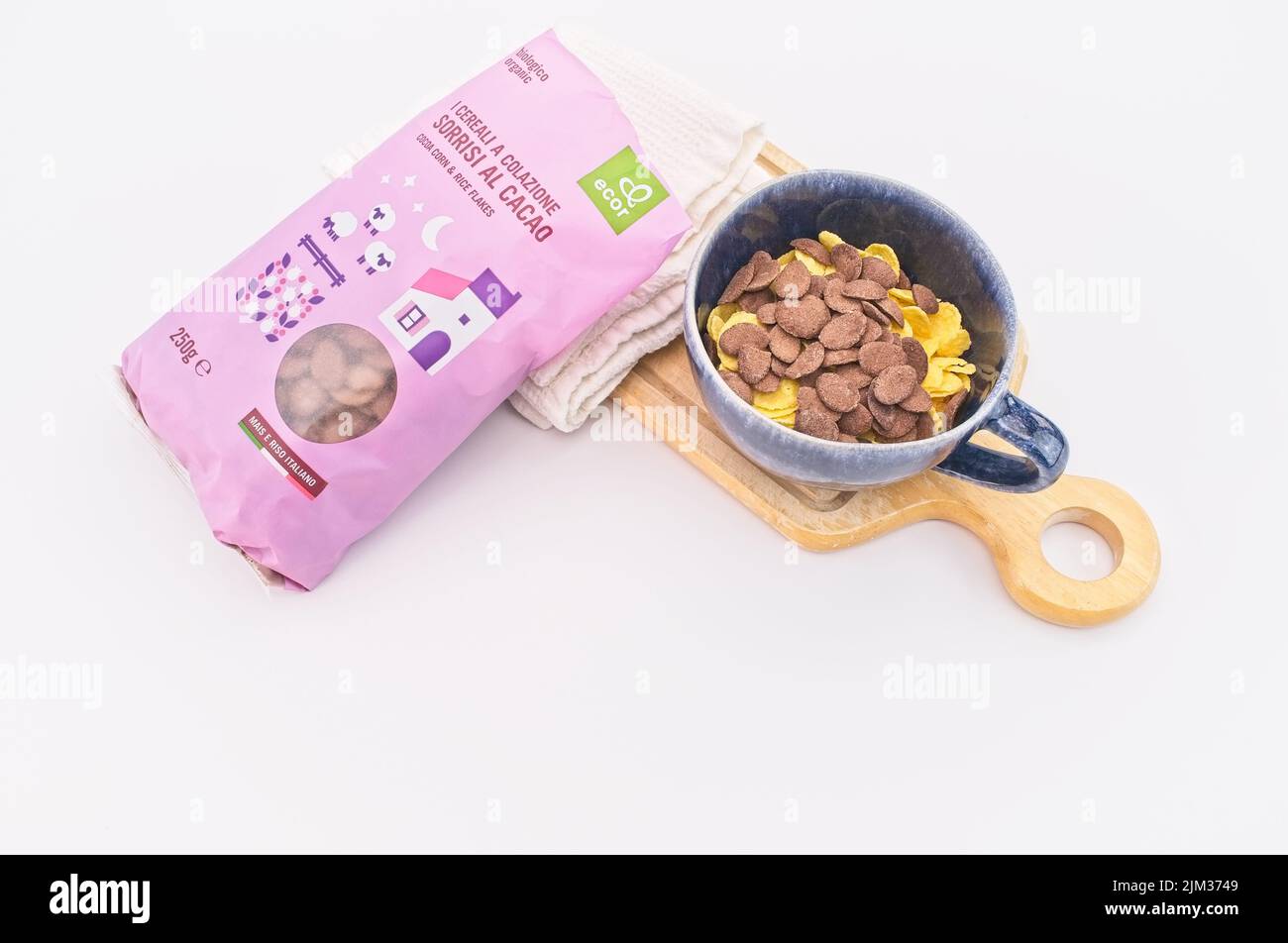 Bio-Anbau von Kakaomorn und Reisflocken mit Schüssel, Schneidebrett und Küchentuch auf einem weißen Tisch Stockfoto
