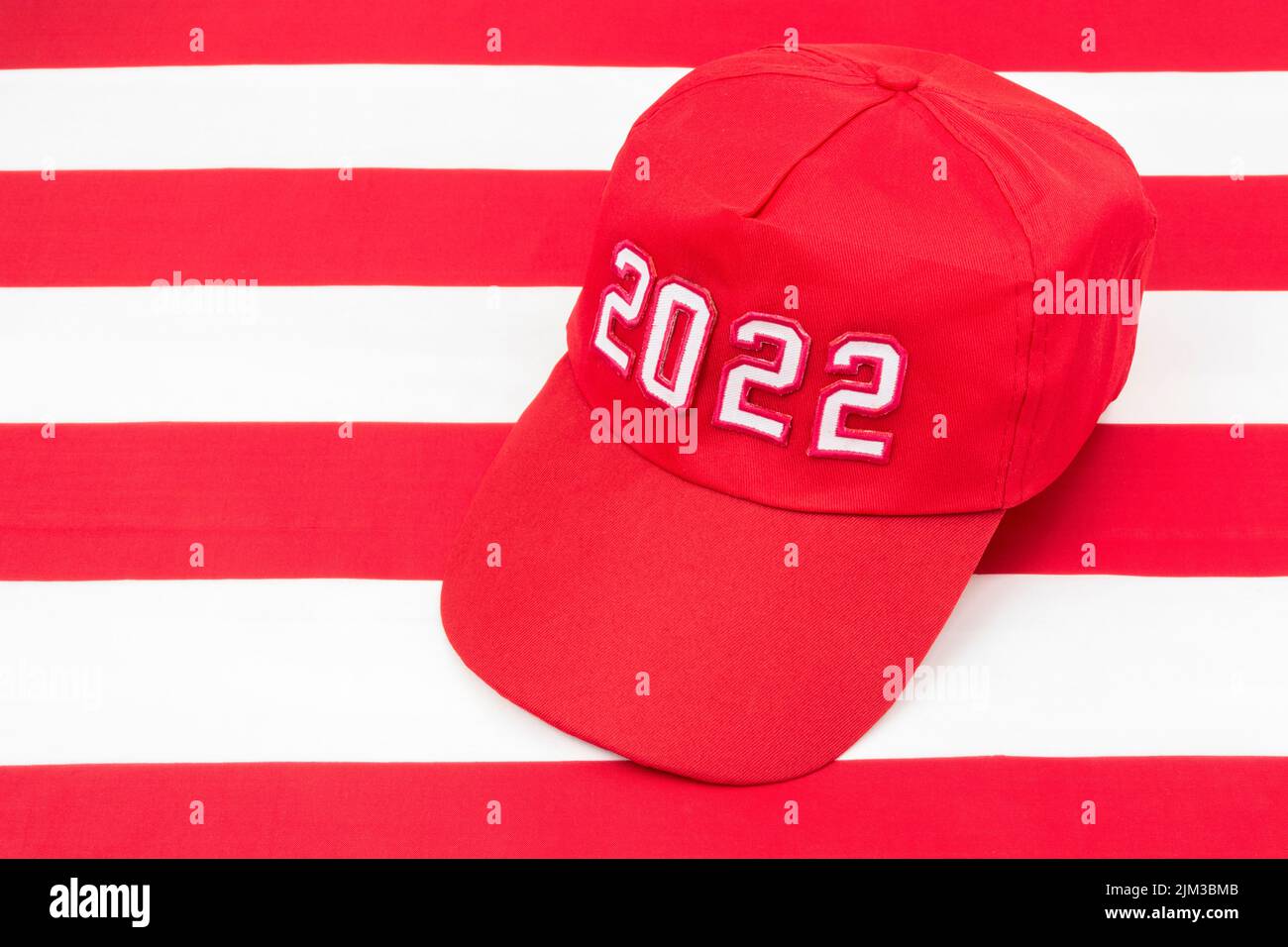 Red MAGA-Typ Hut mit 2022 Datum auf US Stars and Stripes Flagge. Für republikanische Siege bei den Mittelfristwahlen in den USA im November 2022 und der Roten Welle der US-Republikaner Stockfoto