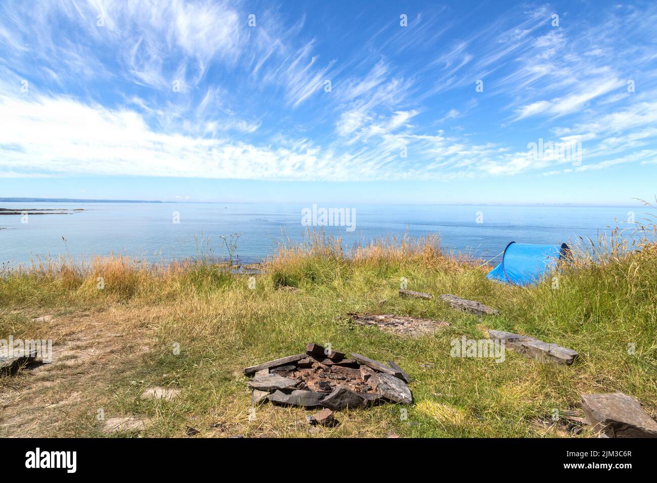 Ein malerischer Blick auf das Meer von einem großen Hügel oder Berg, wo ein Zelt aufgeschlagen wurde, Abenteuerurlaub, wildes Campen, Outdoor-Aktivitäten-Konzept. Stockfoto
