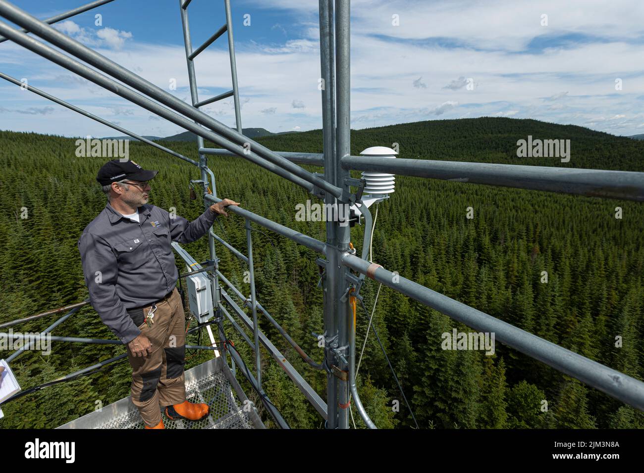 Jean-Francois Lamarre schaut weg, umgeben von wissenschaftlichen Instrumenten auf dem Montmorency Forest Flux Tower Mittwoch, 13. Juli 2022. Gefunden Nein Stockfoto