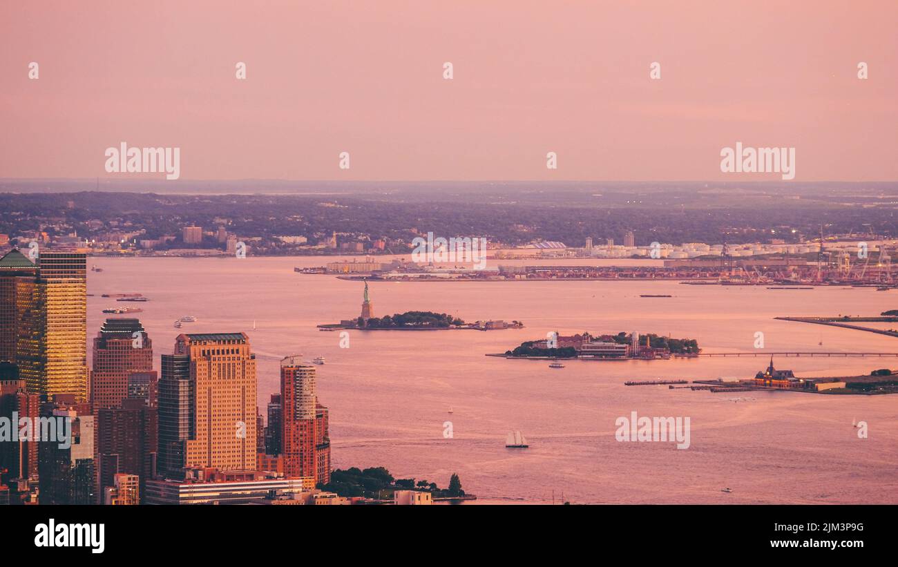 Eine Luftaufnahme von New York City mit Wolkenkratzern und einem Gewässer mit Liberty Island und Elise Island bei Sonnenuntergang Stockfoto