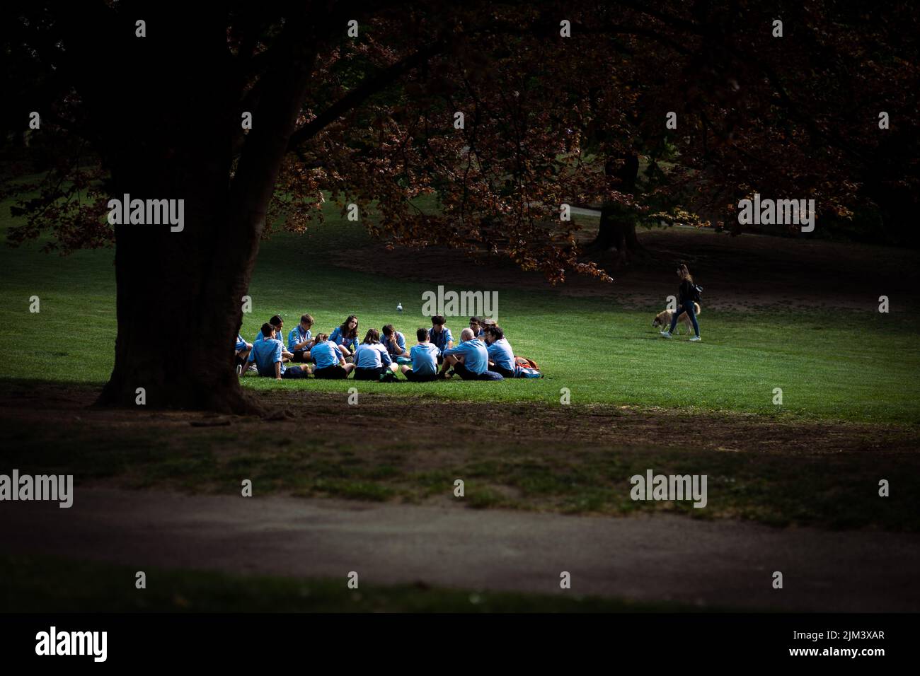Eine Gruppe von Menschen in blauen Hemden, die in einem Park in Turin, Italien, sitzen Stockfoto
