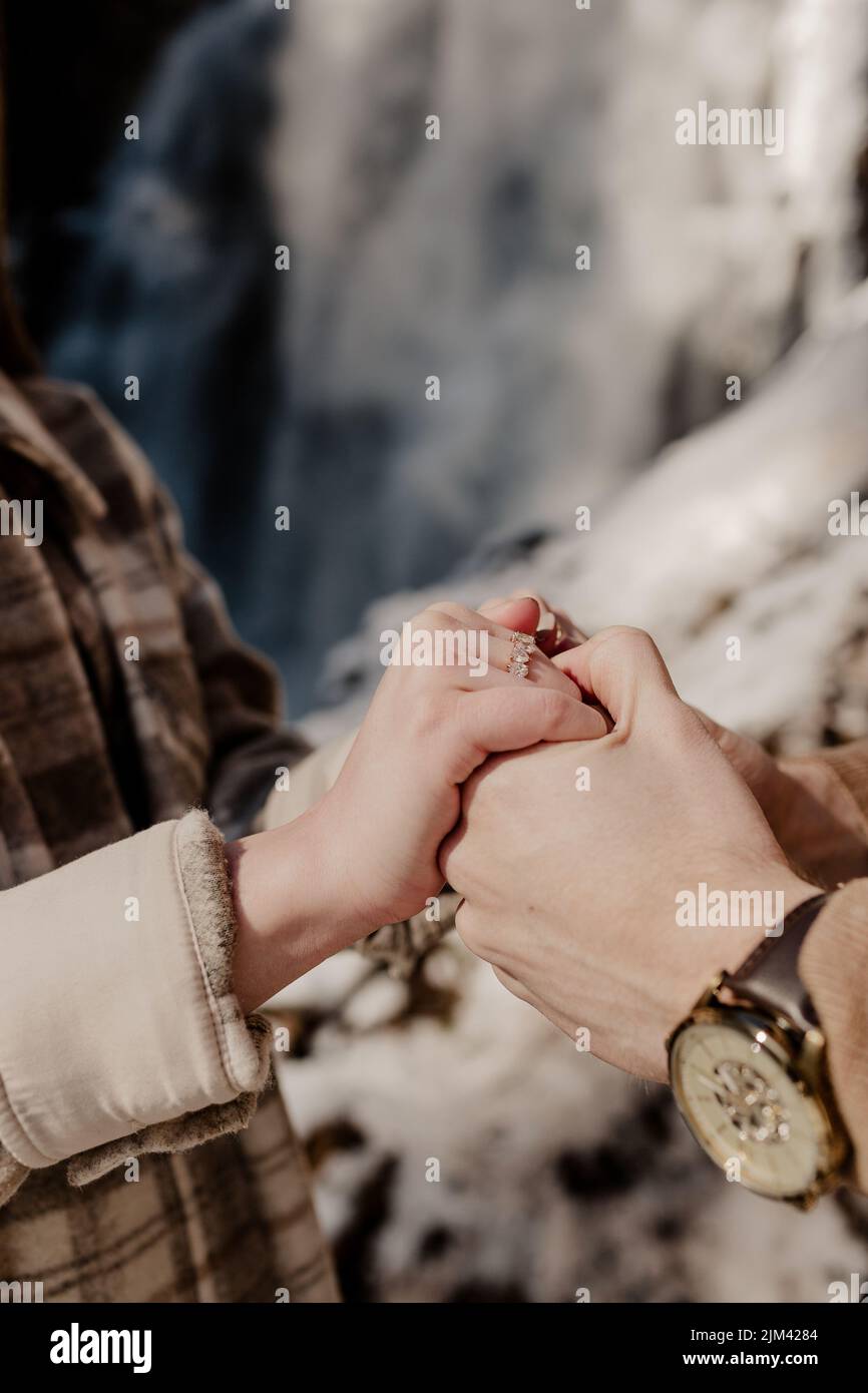 Eine Nahaufnahme der Hände eines Paares, das seinen Verlobungsring zeigt, während es an einem sonnigen Tag in Fall Brook Falls, New Brunswick, Kanada, die Hände hält Stockfoto