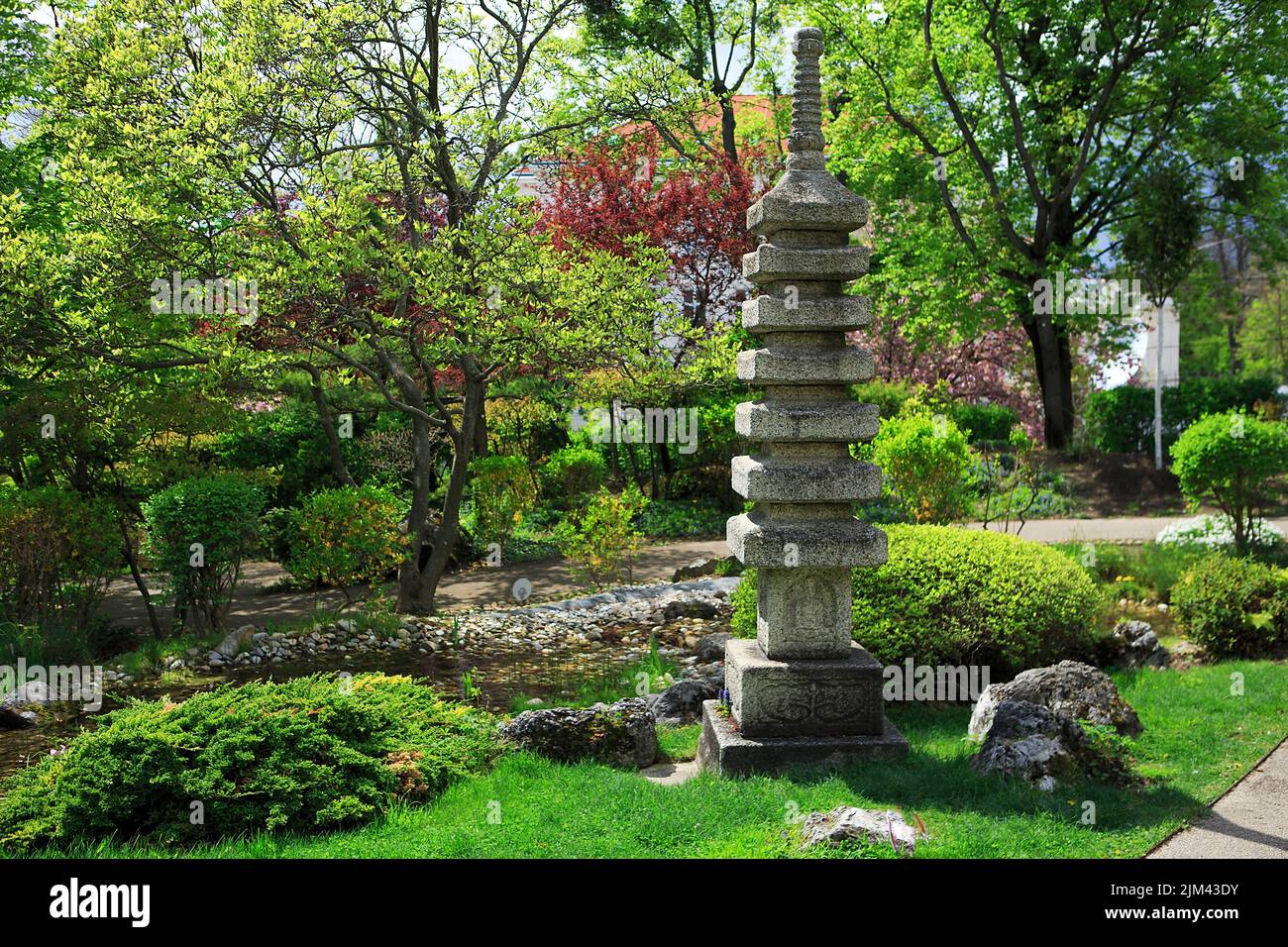 Eine Steinstatue, umgeben von Grün in einem schönen japanischen Garten Stockfoto