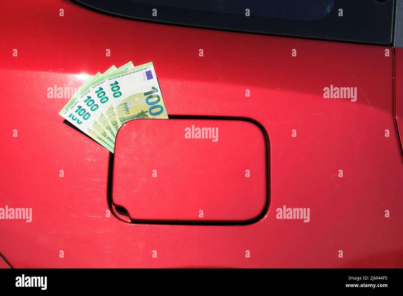 Ein Paket von hundert Euro-Scheinen, die aus einem Tankdeckel ragen, Geld im Tankdeckel eines Autos, das die steigenden Kraftstoffpreise symbolisiert. Stockfoto