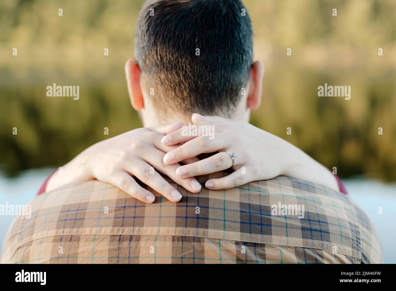 Eine weibliche Hand um den Hals ihres Verlobten - Verlobungsfotos Stockfoto