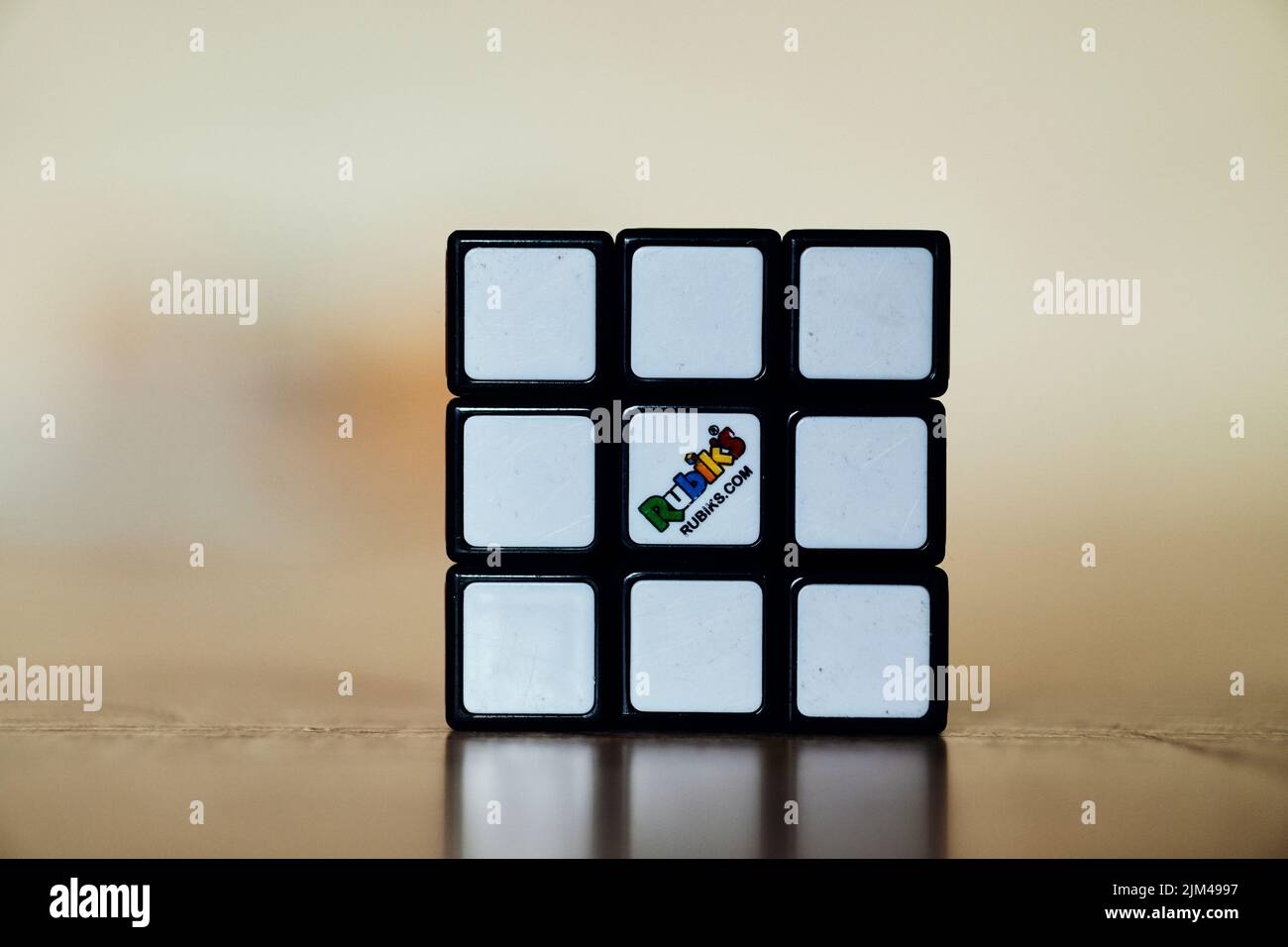 Ein gelöster Rubik-Würfel, der auf einer glänzenden Holzoberfläche steht Stockfoto