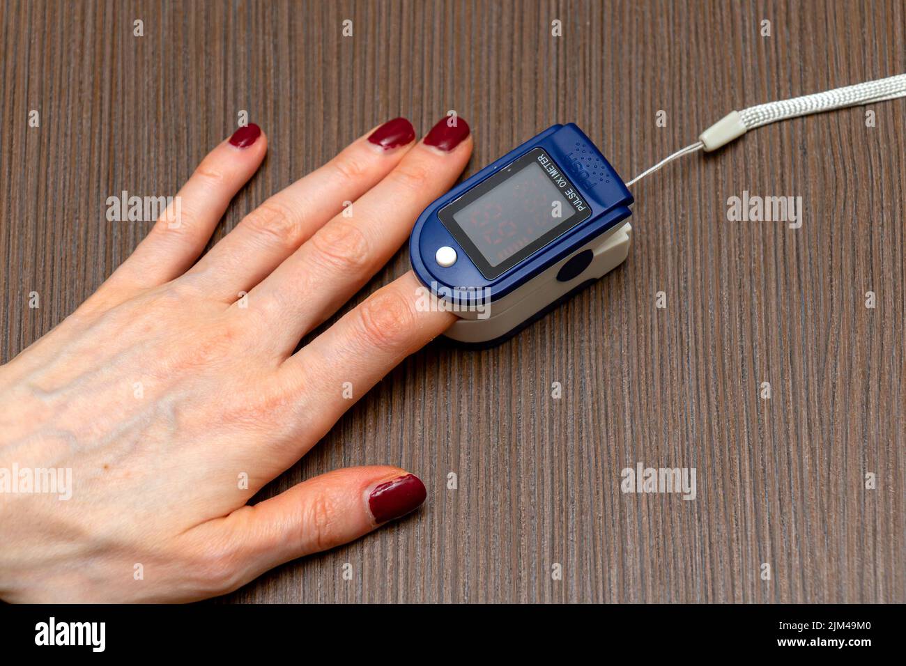 Pulsoximeter am weiblichen Zeigefinger, der die Puls- und Sauerstoffsättigung in roten Blutkörperchen misst Stockfoto