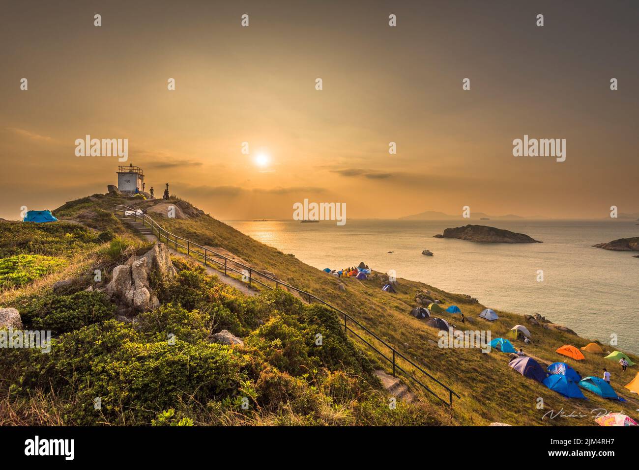 Hong Kong, Po Toi Insel umgeben vom Meer, Touristen mit bunten Zelten sind auf den Felsen der Insel bei Sonnenuntergang Stockfoto