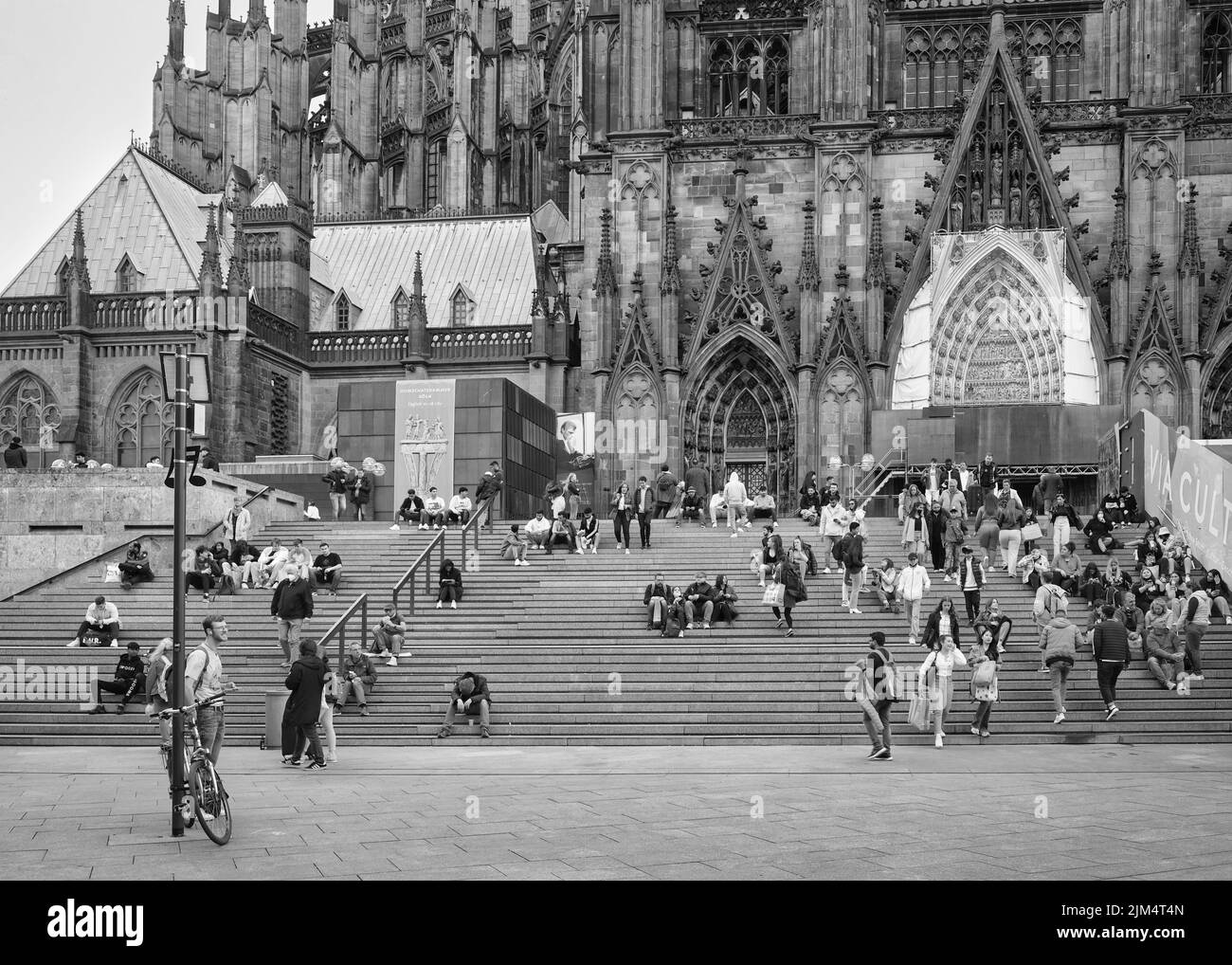Menschen auf der Treppe vor dem Kölner Dom in Richtung Hauptbahnhof, schwarz-weiß Foto Stockfoto