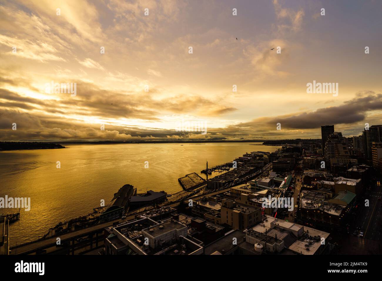 Goldener Sonnenuntergang über der Seattle Waterfront. Blick nach Norden auf den Pike Place Market und die Elliott Bay. Aufnahme vom Dach des Gebäudes. Stockfoto