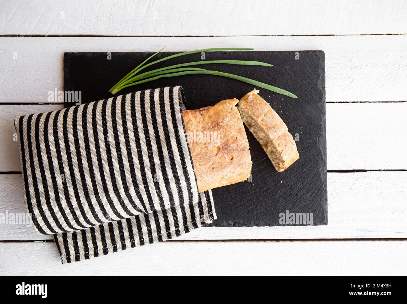 Flat Lay View frisch gebackene hausgemachte Weizenmehl Laib Brot auf schwarzem Stein Servierbrett in der heimischen Küche. Stockfoto