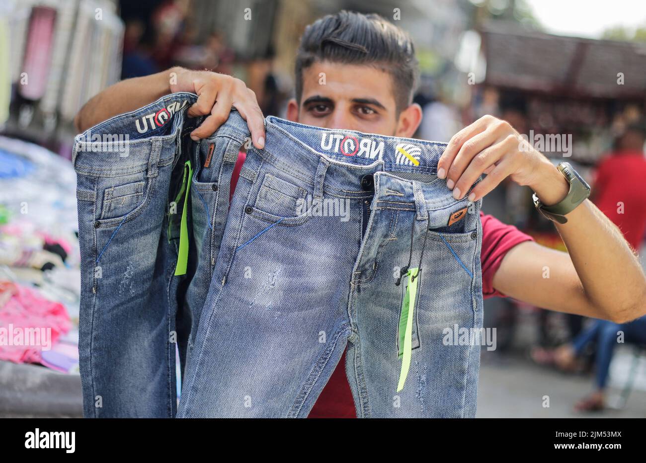 Ein Palästinenser verkauft Kleidung auf einer Straße in Gaza-Stadt. Die Hamas-Führer in Gaza verhängten vor dem neuen Schuljahr eine ganze Reihe neuer Steuern auf importierte Kleidung und Büromaterialien, was begrenzte, aber seltene Proteste in der verarmten Küstenenklave auslöste. Es kommt zu einer Zeit, in der 2,3 Millionen Menschen in Gaza unter der 15 Jahre alten israelischen Blockade leiden, aber auch unter einem neuen Preisanstieg, der durch globale Lieferkettenprobleme und die russische Invasion in der Ukraine verursacht wird. Die Liste des Wirtschaftsministeriums enthält geplante Steuern auf Artikel wie verpackte Nüsse mit einem Einfuhrtarif von 2.000 Schekel (etwa 600 Dollar) pro Stück Stockfoto