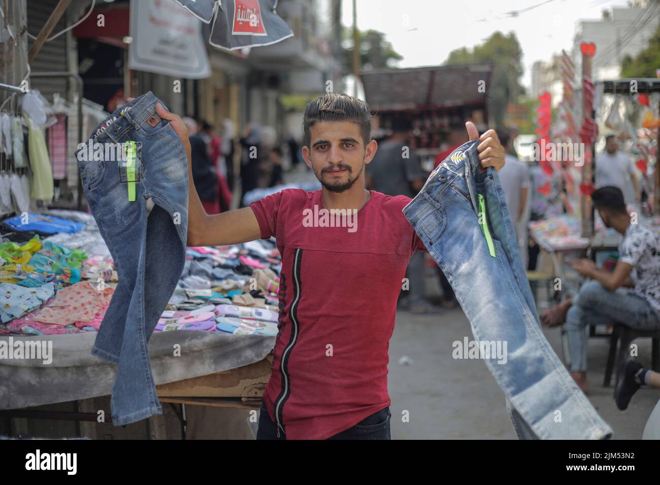 Ein Palästinenser verkauft Kleidung auf einer Straße in Gaza-Stadt. Die Hamas-Führer in Gaza verhängten vor dem neuen Schuljahr eine ganze Reihe neuer Steuern auf importierte Kleidung und Büromaterialien, was begrenzte, aber seltene Proteste in der verarmten Küstenenklave auslöste. Es kommt zu einer Zeit, in der 2,3 Millionen Menschen in Gaza unter der 15 Jahre alten israelischen Blockade leiden, aber auch unter einem neuen Preisanstieg, der durch globale Lieferkettenprobleme und die russische Invasion in der Ukraine verursacht wird. Die Liste des Wirtschaftsministeriums enthält geplante Steuern auf Artikel wie verpackte Nüsse mit einem Einfuhrtarif von 2.000 Schekel (etwa 600 Dollar) pro Stück Stockfoto