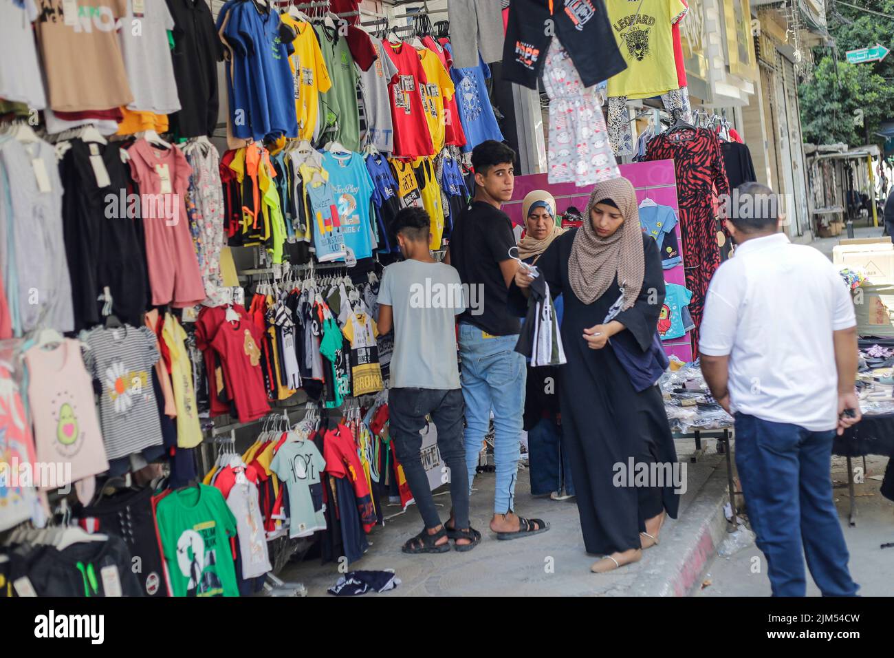 Palästinenser sahen in einem Bekleidungsgeschäft in Gaza-Stadt einkaufen. Die Hamas-Führer in Gaza verhängten vor dem neuen Schuljahr eine ganze Reihe neuer Steuern auf importierte Kleidung und Büromaterialien, was begrenzte, aber seltene Proteste in der verarmten Küstenenklave auslöste. Es kommt zu einer Zeit, in der 2,3 Millionen Menschen in Gaza unter der 15 Jahre alten israelischen Blockade leiden, aber auch unter einem neuen Preisanstieg, der durch globale Lieferkettenprobleme und die russische Invasion in der Ukraine verursacht wird. Die Liste des Wirtschaftsministeriums enthält geplante Steuern auf Artikel wie verpackte Nüsse mit einem Einfuhrtarif von 2.000 Schekel (ca. 600 Dollar) Stockfoto