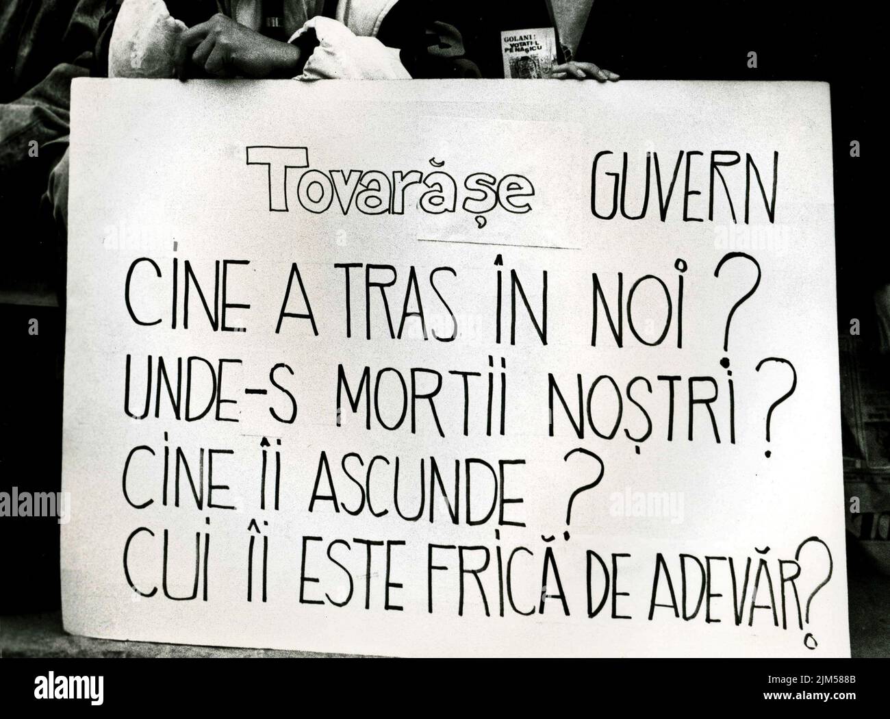Bukarest, Rumänien, Januar 1990. Kundgebung auf dem Universitätsplatz nach der rumänischen Revolution von 1989. Die Menschen versammelten sich täglich, um gegen die ehemaligen kommunistischen Beamten zu protestieren, die nach der Revolution die Macht ergriffen hatten. Auf einem Transparent steht: "Genosse Regierung, wer erschießt uns? Wo sind die Toten? Wer versteckt sie? Wer hat Angst vor der Wahrheit?“ Stockfoto