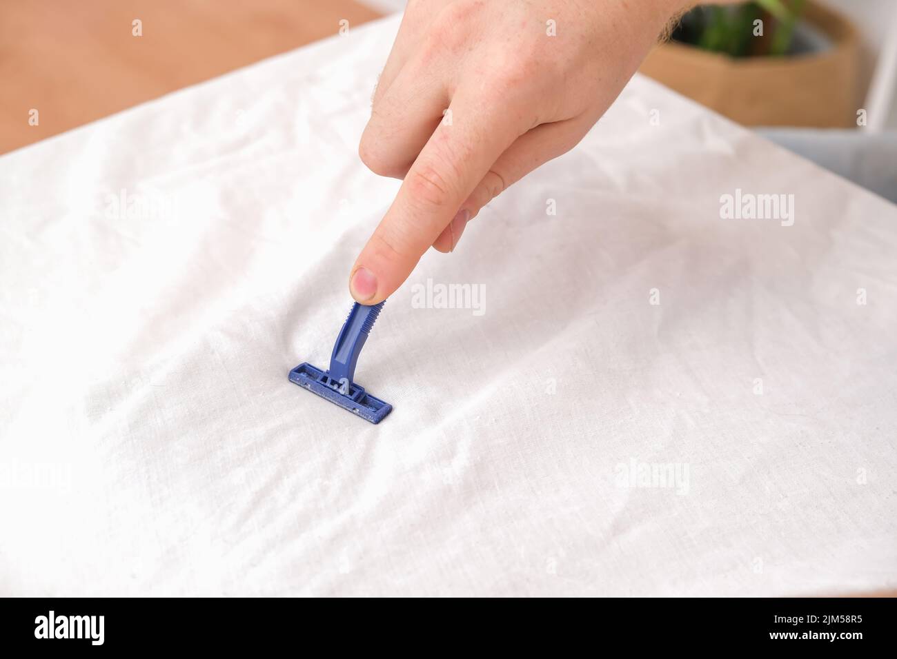 Ein Mann entfernt Stofftabletten mit einer Einweg-Rasiermaschine. Ein Rasiermesser zum Entfernen von Pellets. Stockfoto