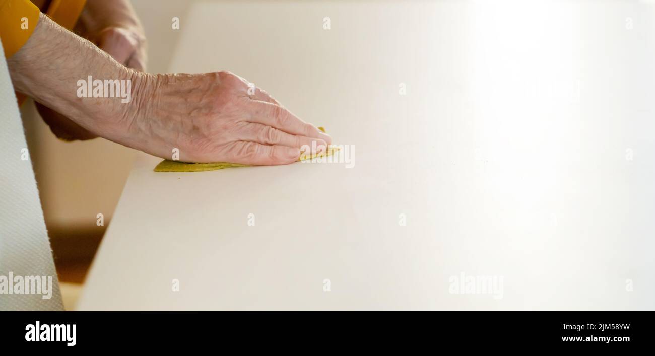 Die alte Frau putzt das Haus, Hand mit einem Lappen aus der Nähe. Stockfoto