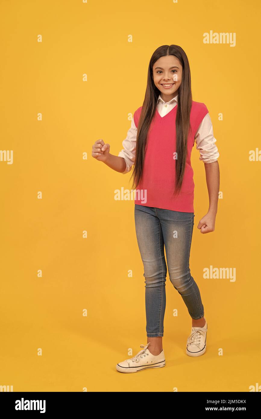 Happy teen Schulmädchen zu Fuß auf gelbem Hintergrund, kopieren Raum, Mode Stockfoto